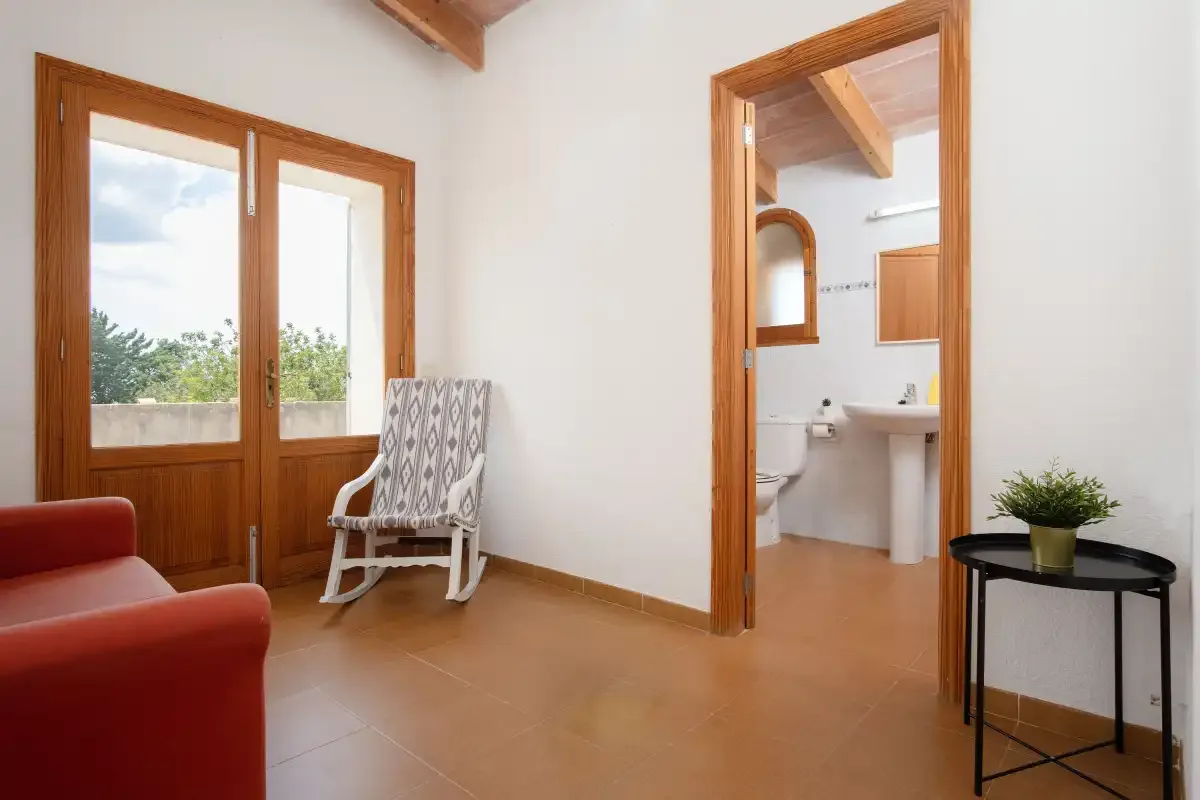 A bright interior room with wooden doors opening onto a bathroom and a potted plant.