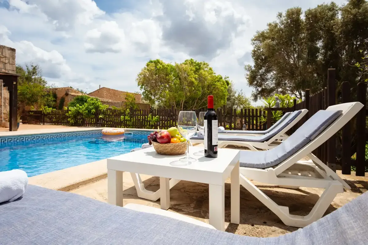 A poolside patio with lounge seating and a small table beside the water.