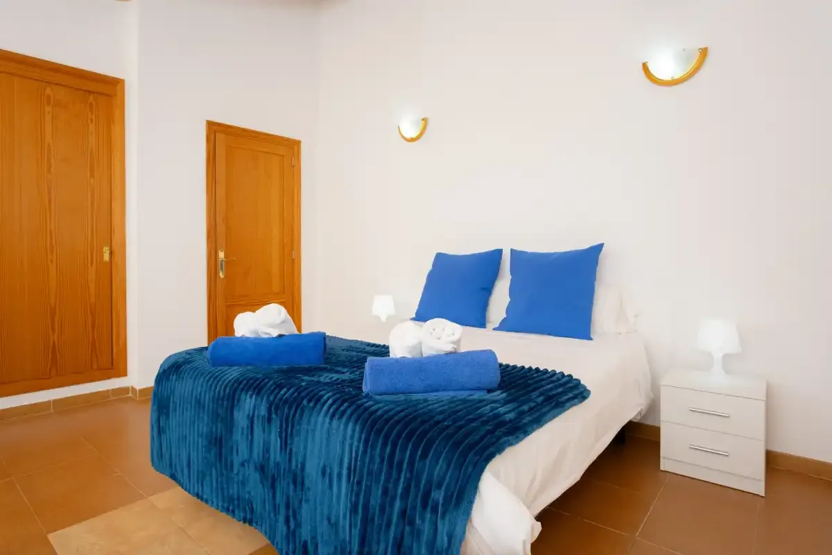 A bedroom with a bed dressed in white and blue linens.