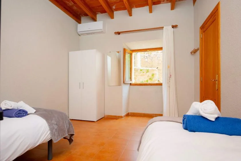A bedroom with two beds, a wardrobe, and a window.