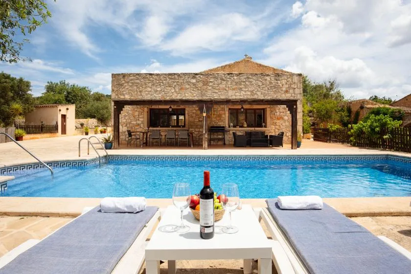A swimming pool with lounge chairs in front of a stone building.