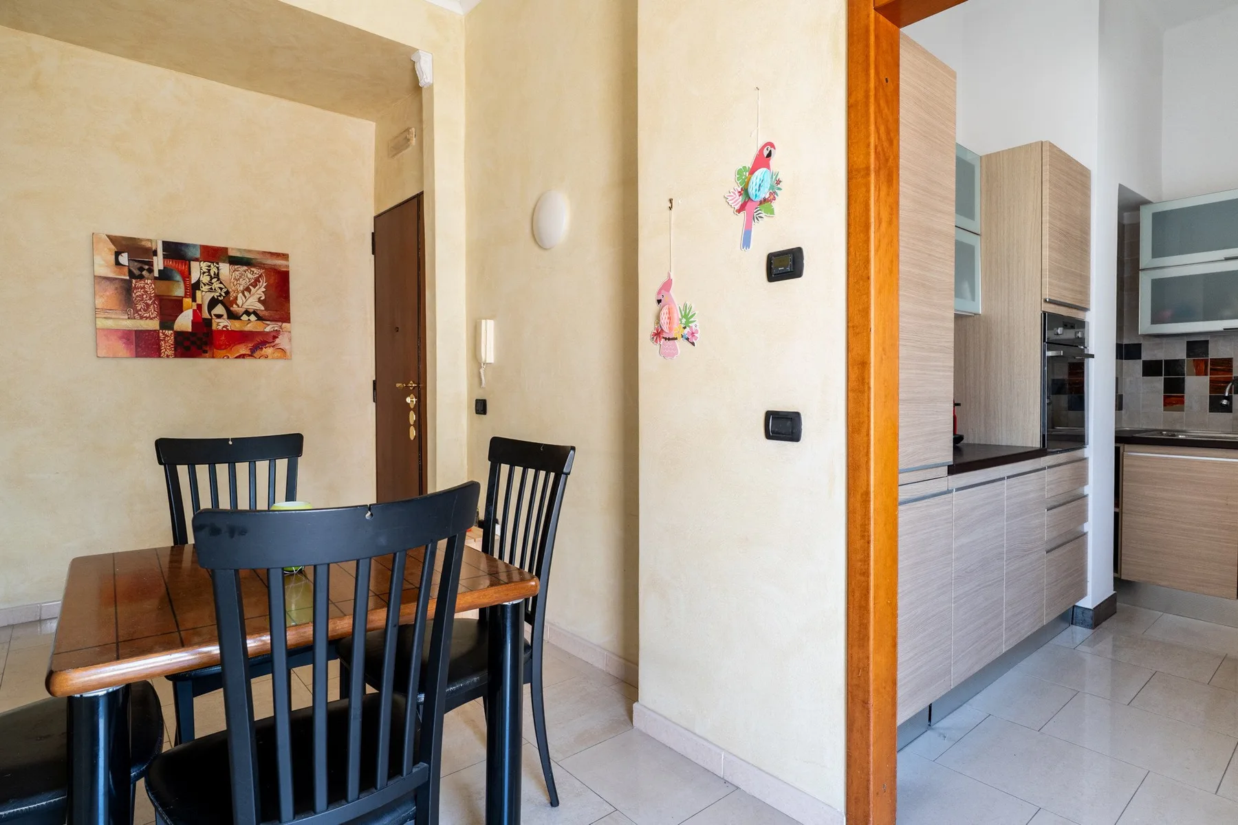 Comedor con una mesa de madera y sillas oscuras junto a una cocina.
