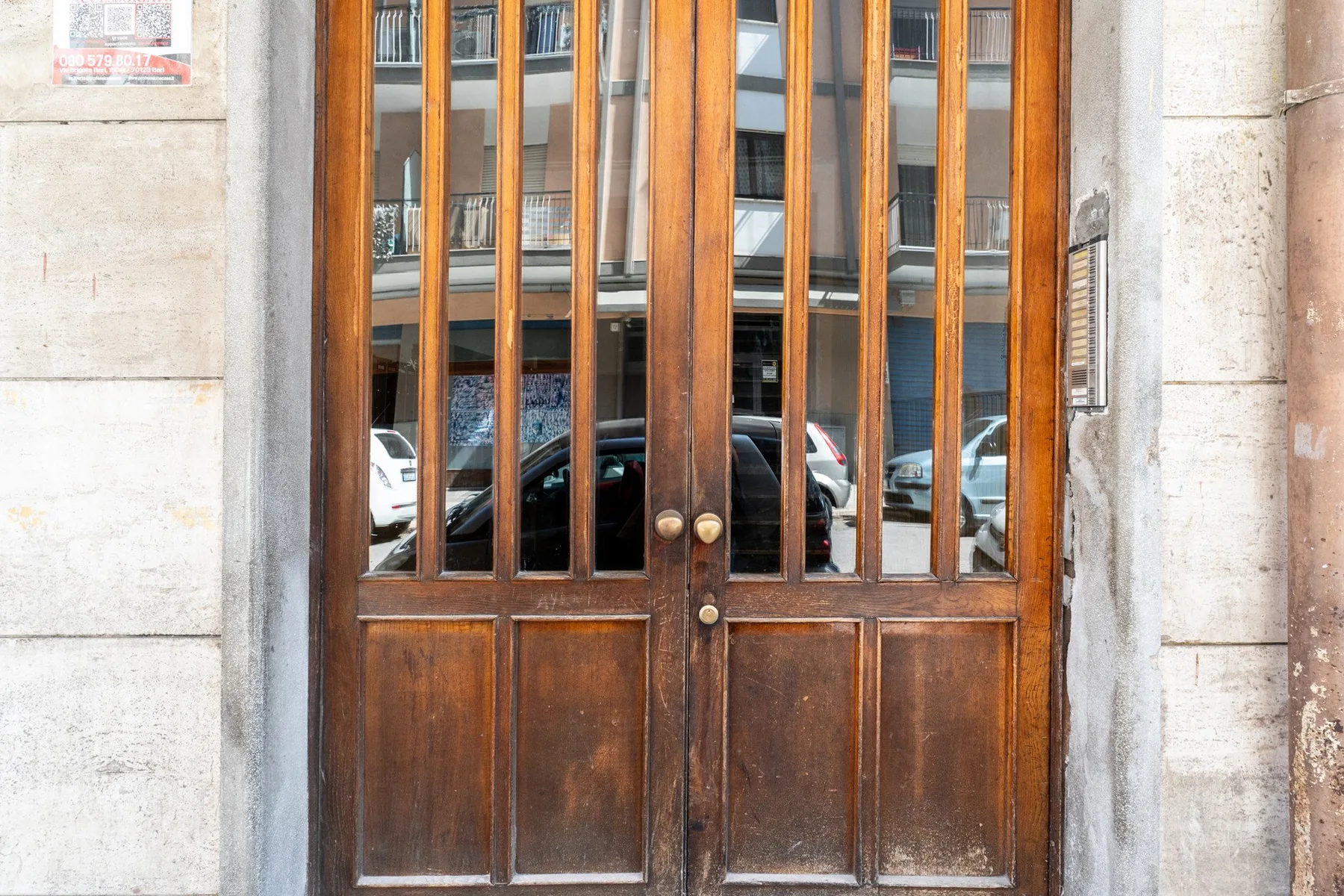 Una puerta de entrada de madera con paneles de vidrio en una fachada de piedra.