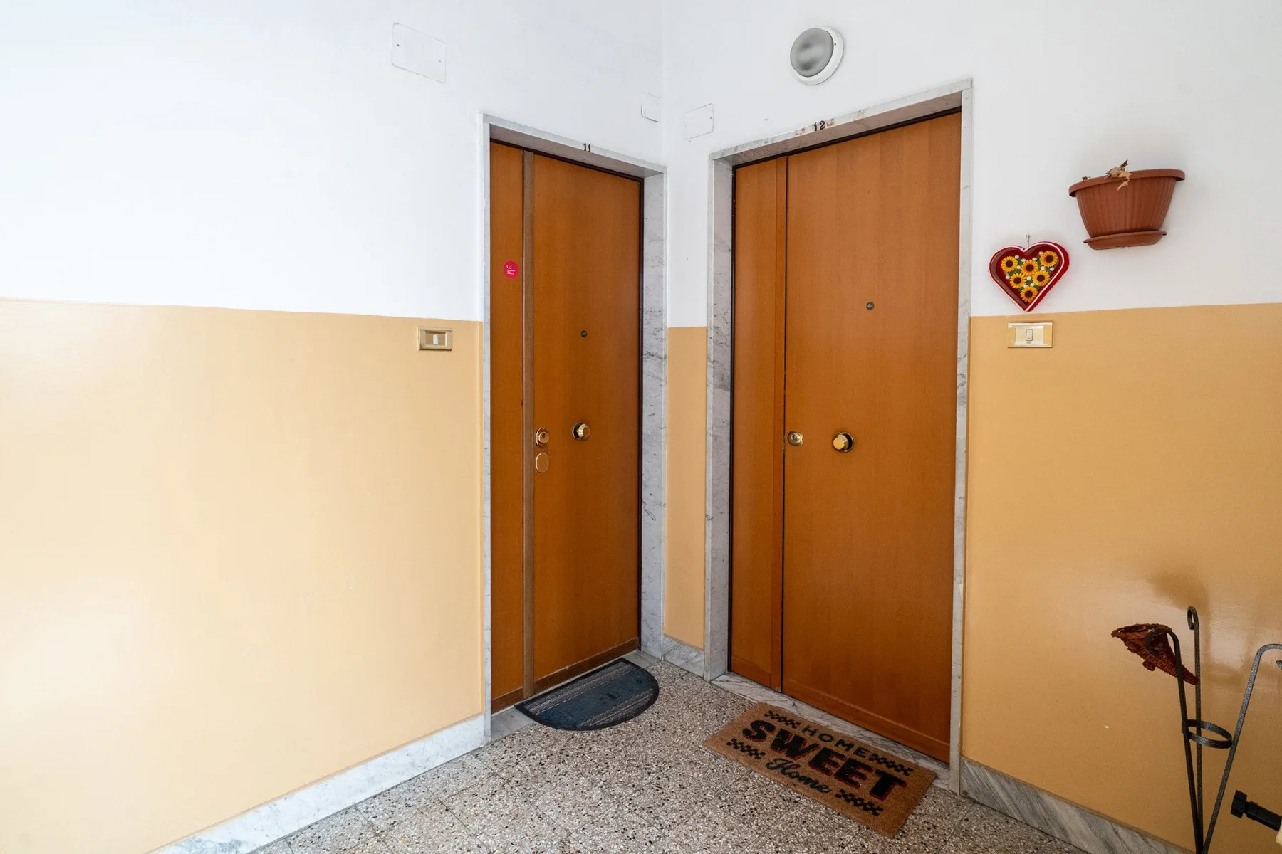 Un pasillo interior con dos puertas de madera y felpudos.