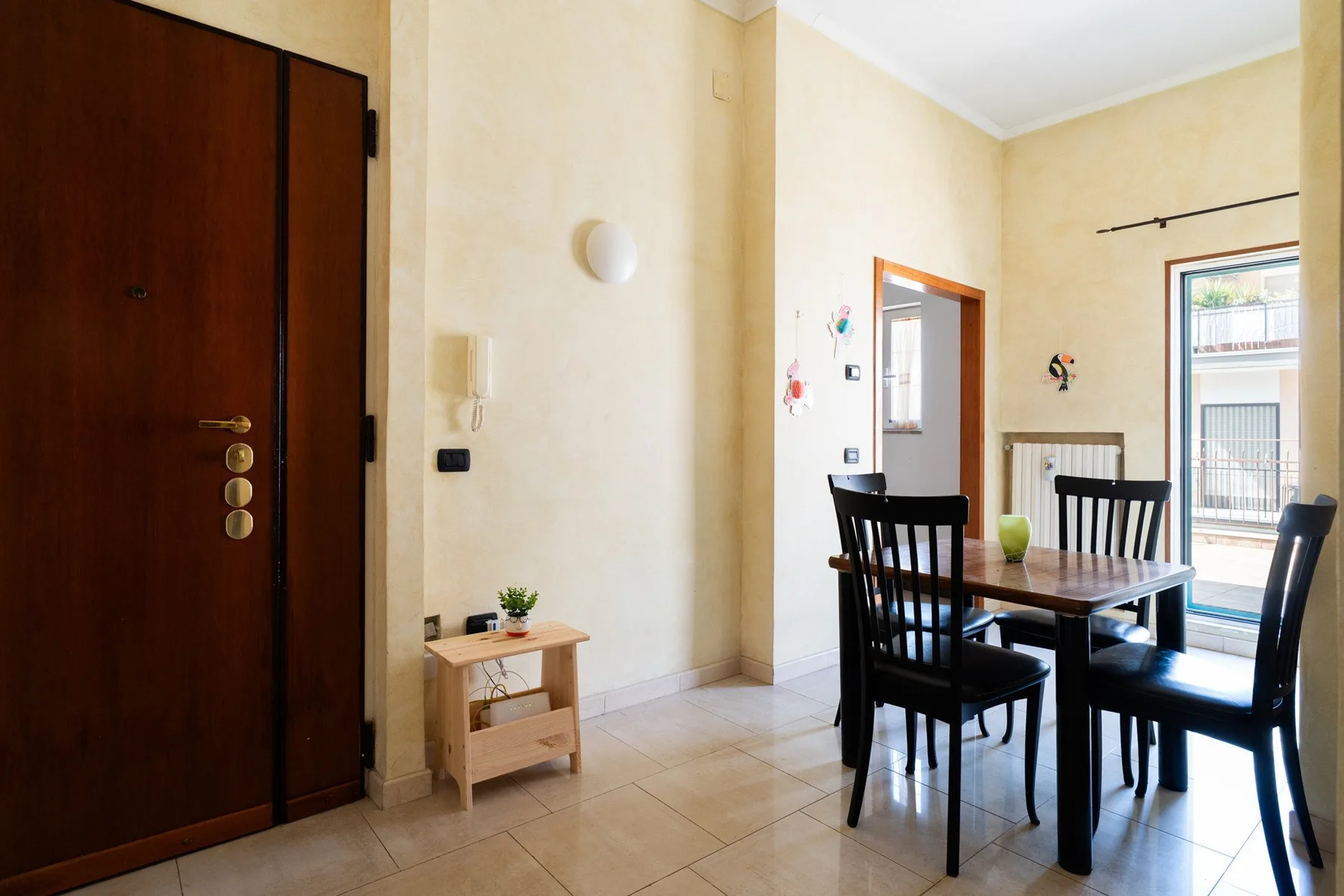 Comedor con una mesa de madera y asientos negros junto a una ventana luminosa.