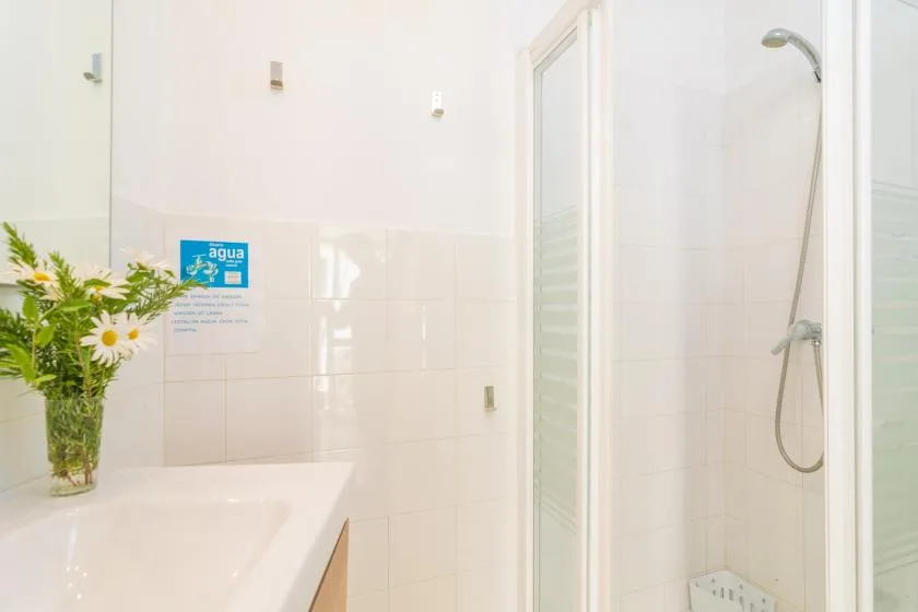 A bright tiled bathroom with a sink and shower.