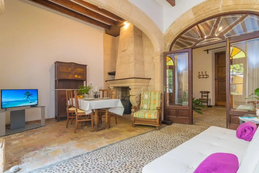 A living room with a dining table, fireplace, and open arched doorway.