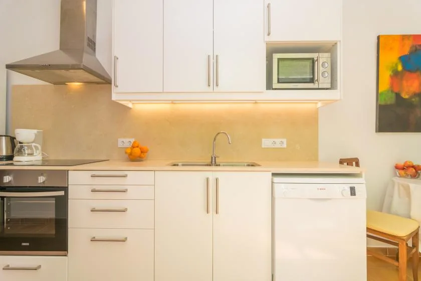 A modern kitchen with white cabinets, a cooktop, and a sink.
