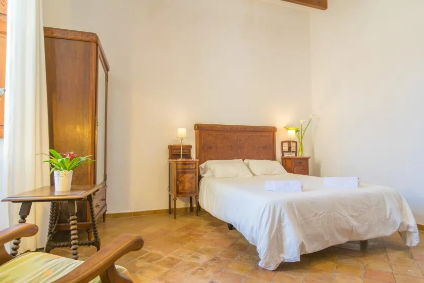 A bedroom with a double bed, wooden furniture, and tiled flooring.