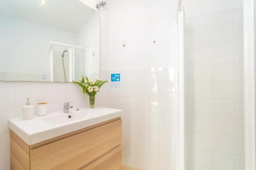 A bright bathroom with a sink vanity and a glass shower.
