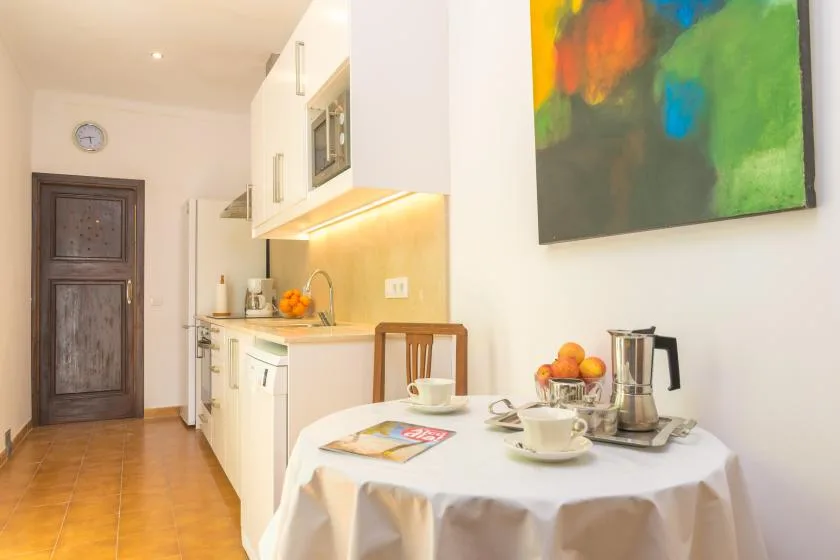 A compact kitchen opens onto a dining area with a table set for coffee.