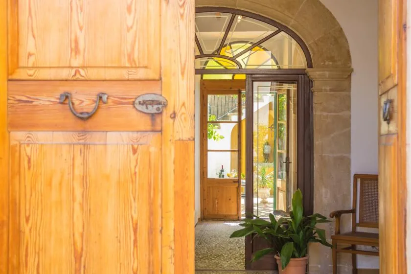 An arched entryway with an open wooden door and a potted plant.