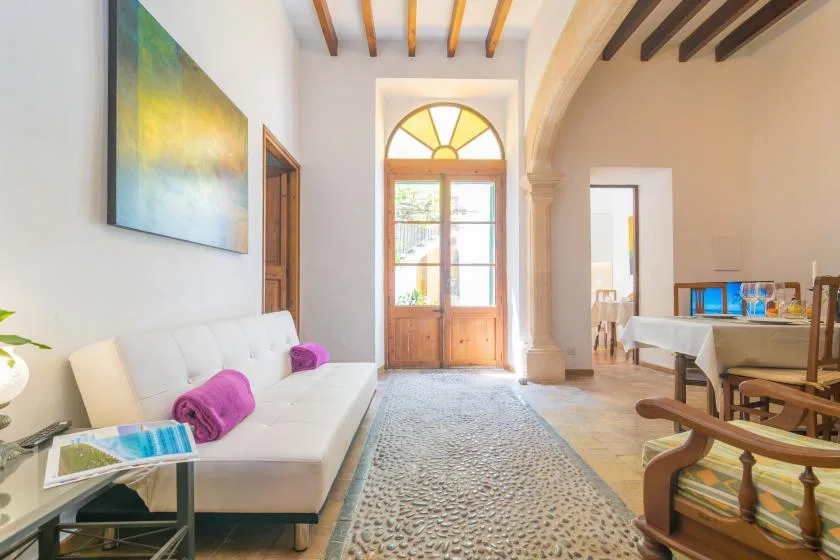 A bright living room with a white seating area and a glass-paneled wooden door.