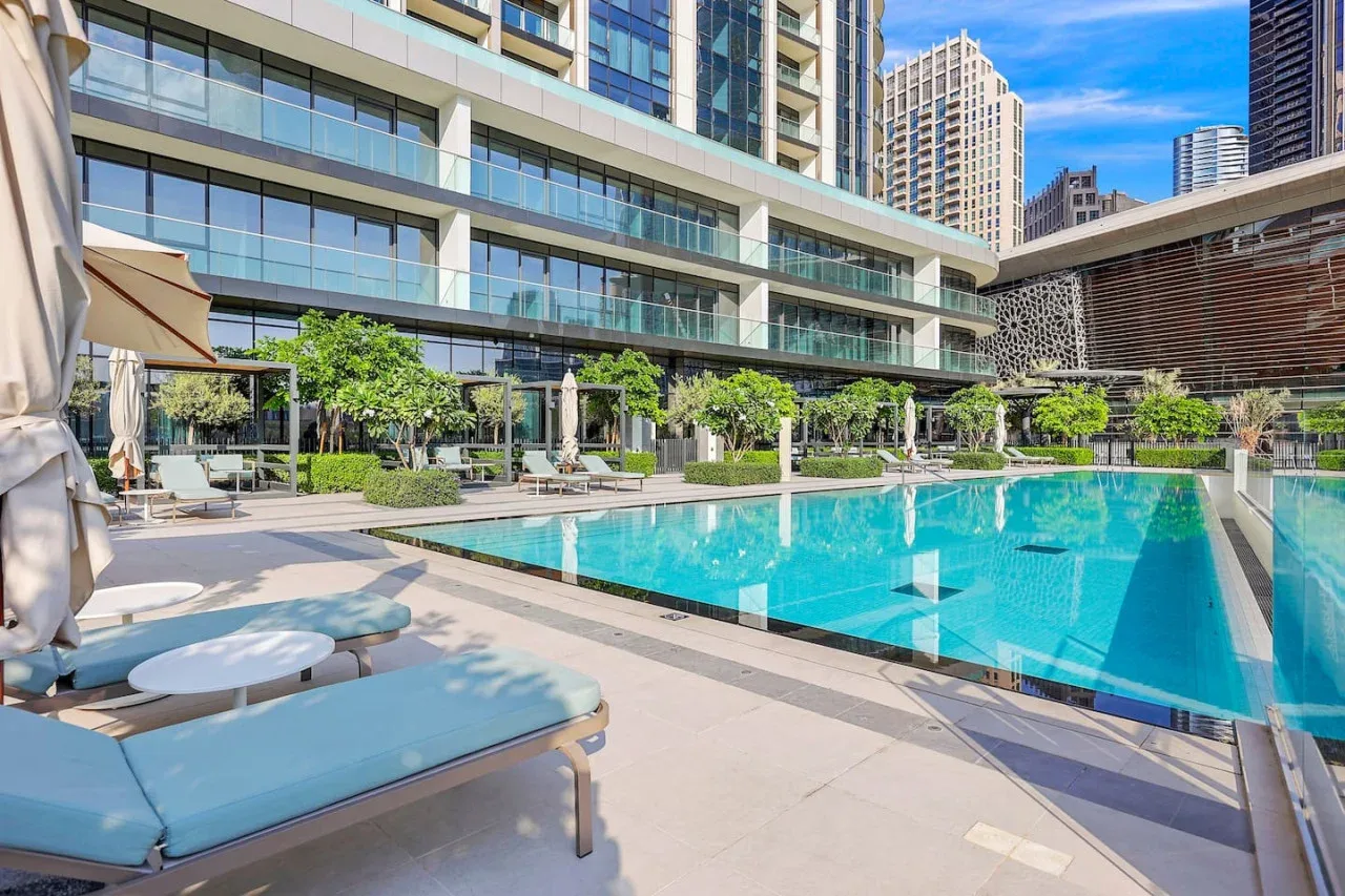 Una piscina al aire libre junto a un edificio moderno con fachada de vidrio.