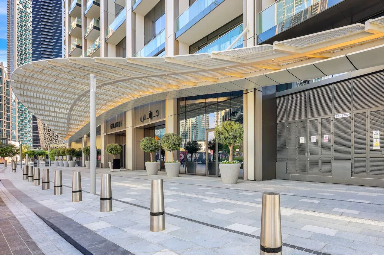 Entrada de un edificio moderno con escaparates de vidrio bajo una amplia marquesina.