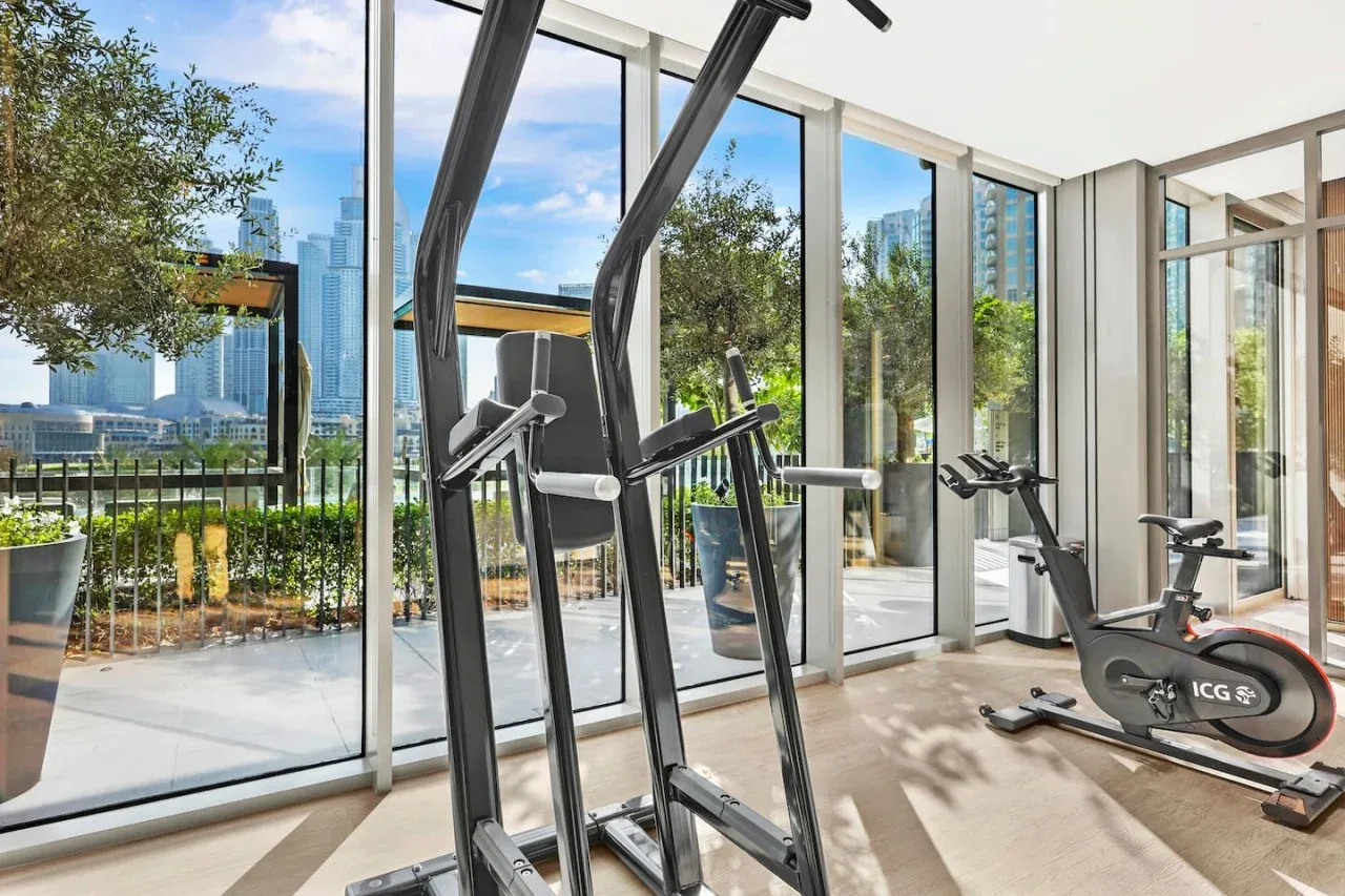 Un gimnasio luminoso con máquinas de ejercicio junto a ventanales.