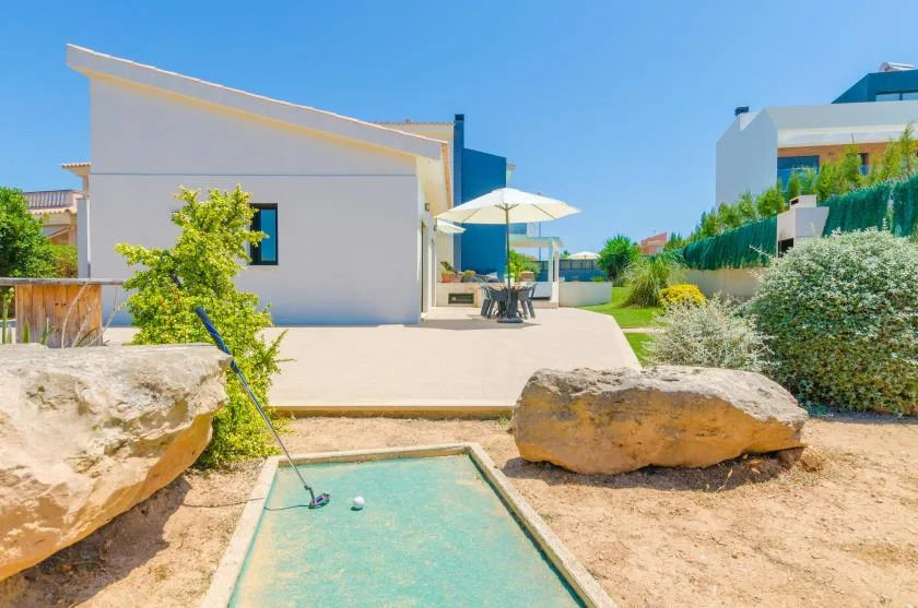 A sunny outdoor patio with a shaded seating area and a small rectangular water feature.