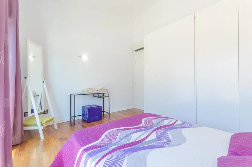 A bedroom with a bed covered in a striped purple and white bedspread.