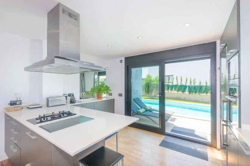 A modern kitchen opens onto a patio with a swimming pool.