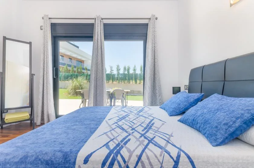 A bedroom with blue bedding and glass doors opening onto a patio.