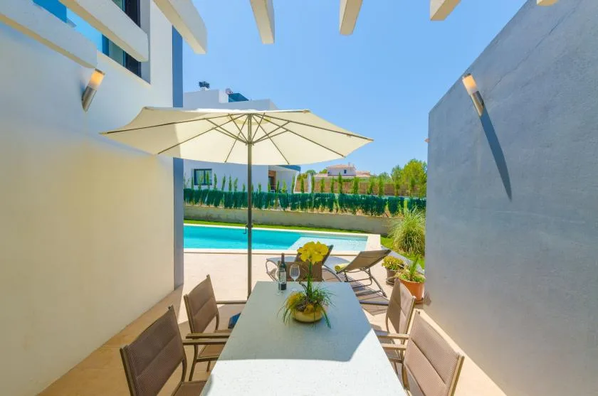 An outdoor dining area with a table and umbrella overlooks a swimming pool.