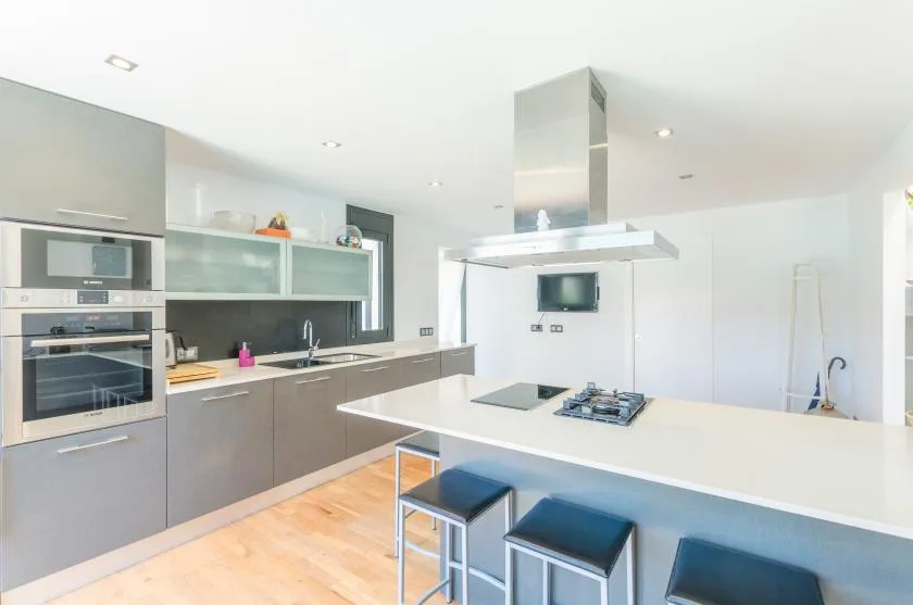 A modern kitchen with a large island, cooktop, and built-in appliances.