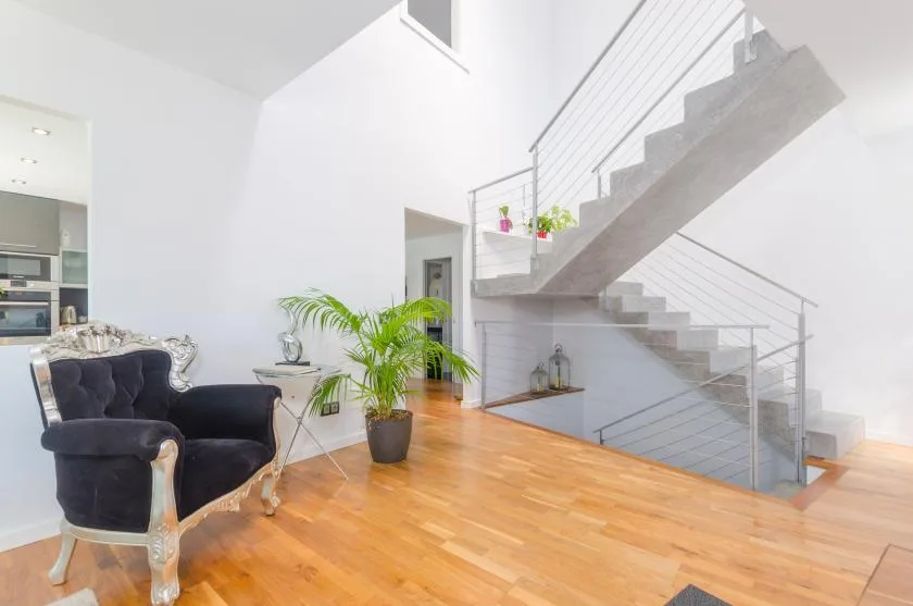 A bright living area with dark seating, a potted plant, and a staircase.