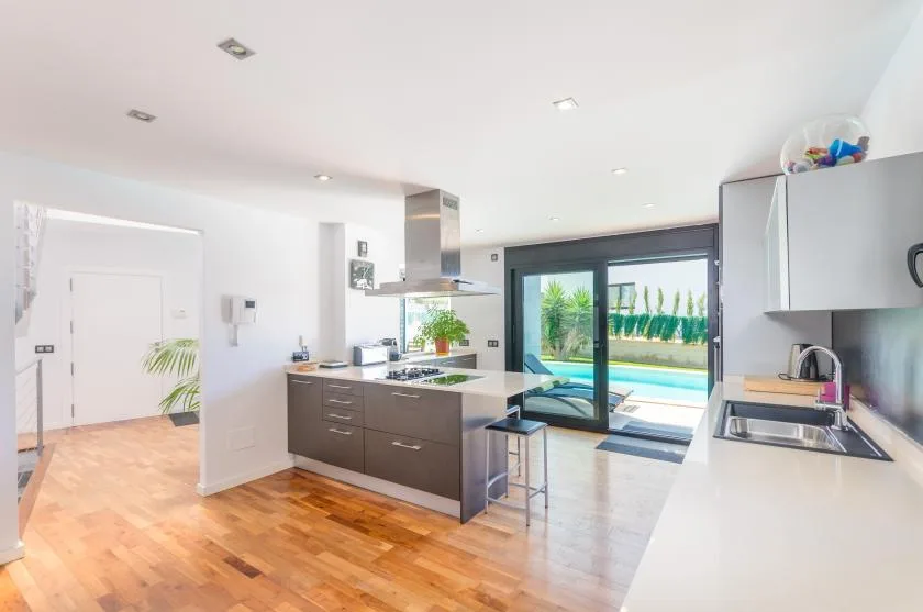 A bright modern kitchen opens onto a patio through large glass doors.