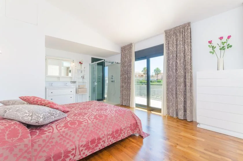 A bedroom with a patterned bedspread and glass doors opening onto a balcony.