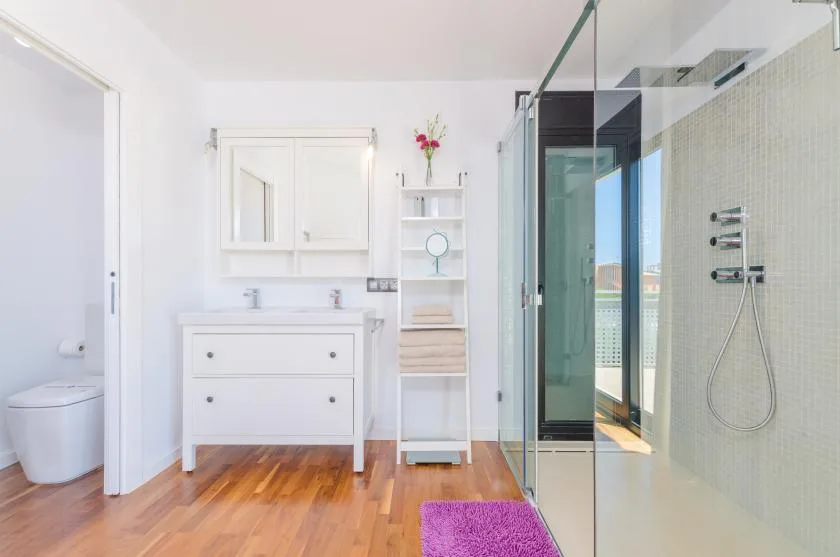 A bright bathroom with a vanity, toilet, and glass shower.