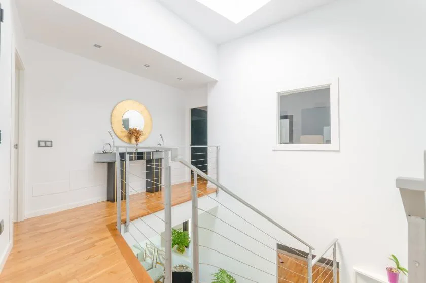 A bright interior landing with a metal railing and a round wall mirror.