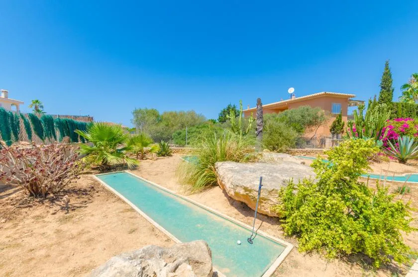 A landscaped outdoor pool area with clear water, rocks, and surrounding plants.