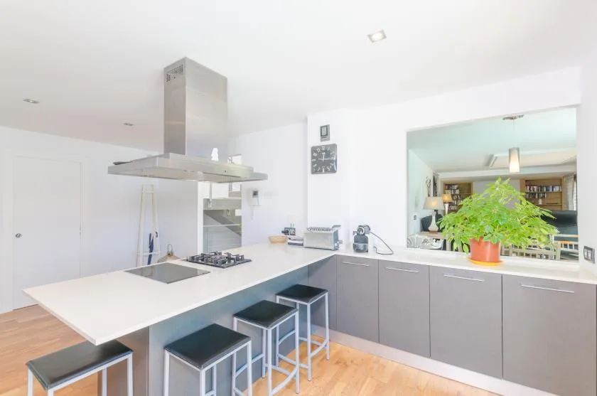 A bright modern kitchen with a large island, cooktop, and bar seating.