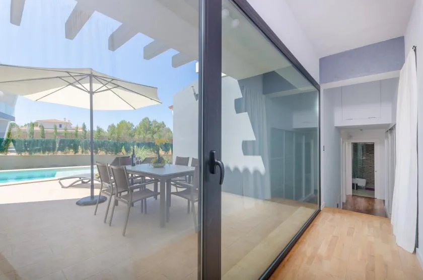 A sliding glass door opens onto a patio with outdoor seating and a pool.