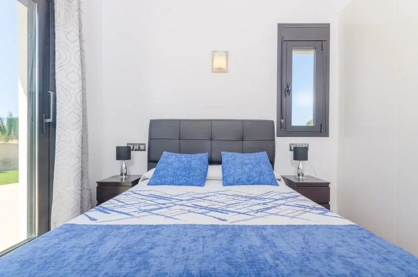 A bedroom with a bed dressed in blue and white bedding.