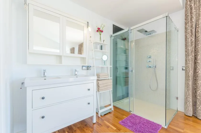 A bright bathroom with a glass shower and white vanity.