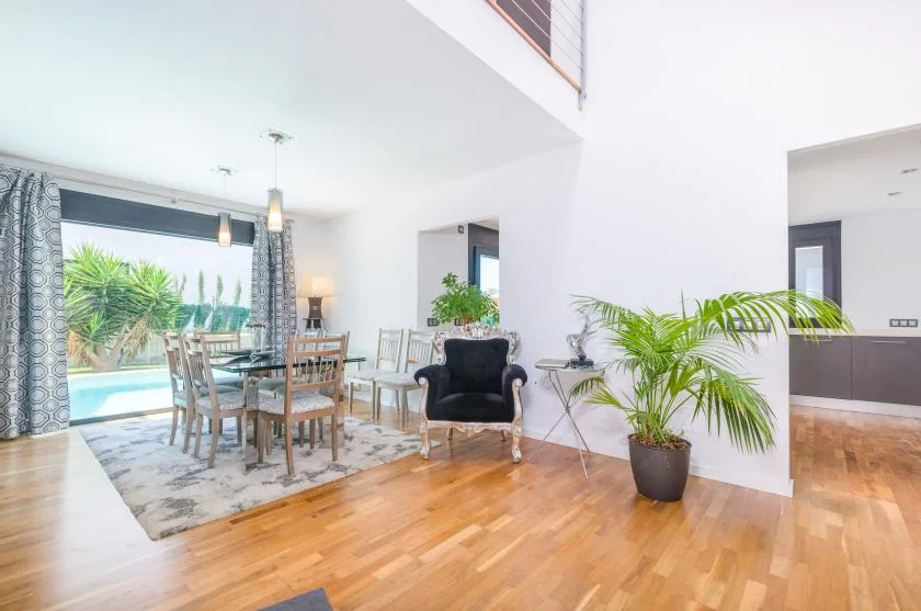 A bright dining and sitting area opens onto a patio through large glass doors.