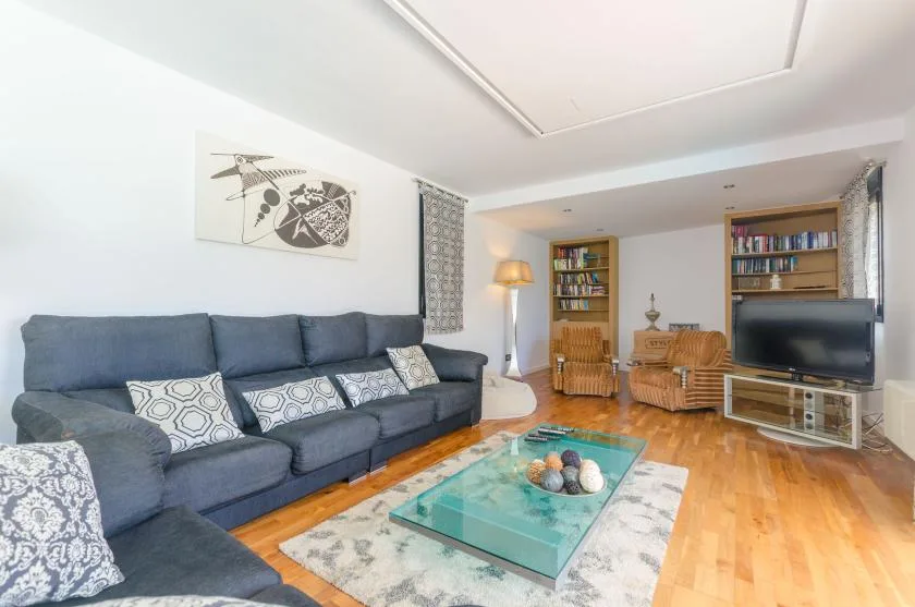 A living room with a blue seating area, glass coffee table, and television.