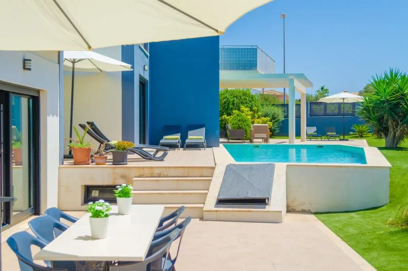 A sunny patio with outdoor seating and a small swimming pool beside a modern house.