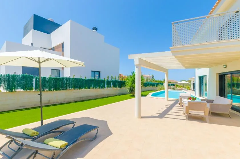 A modern outdoor pool area with sun loungers and a shaded patio.