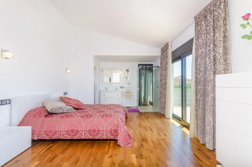 A bedroom with a patterned bed and sliding glass doors opening onto a balcony.