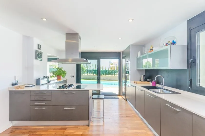 A bright modern kitchen with a central island and glass doors opening to a patio.