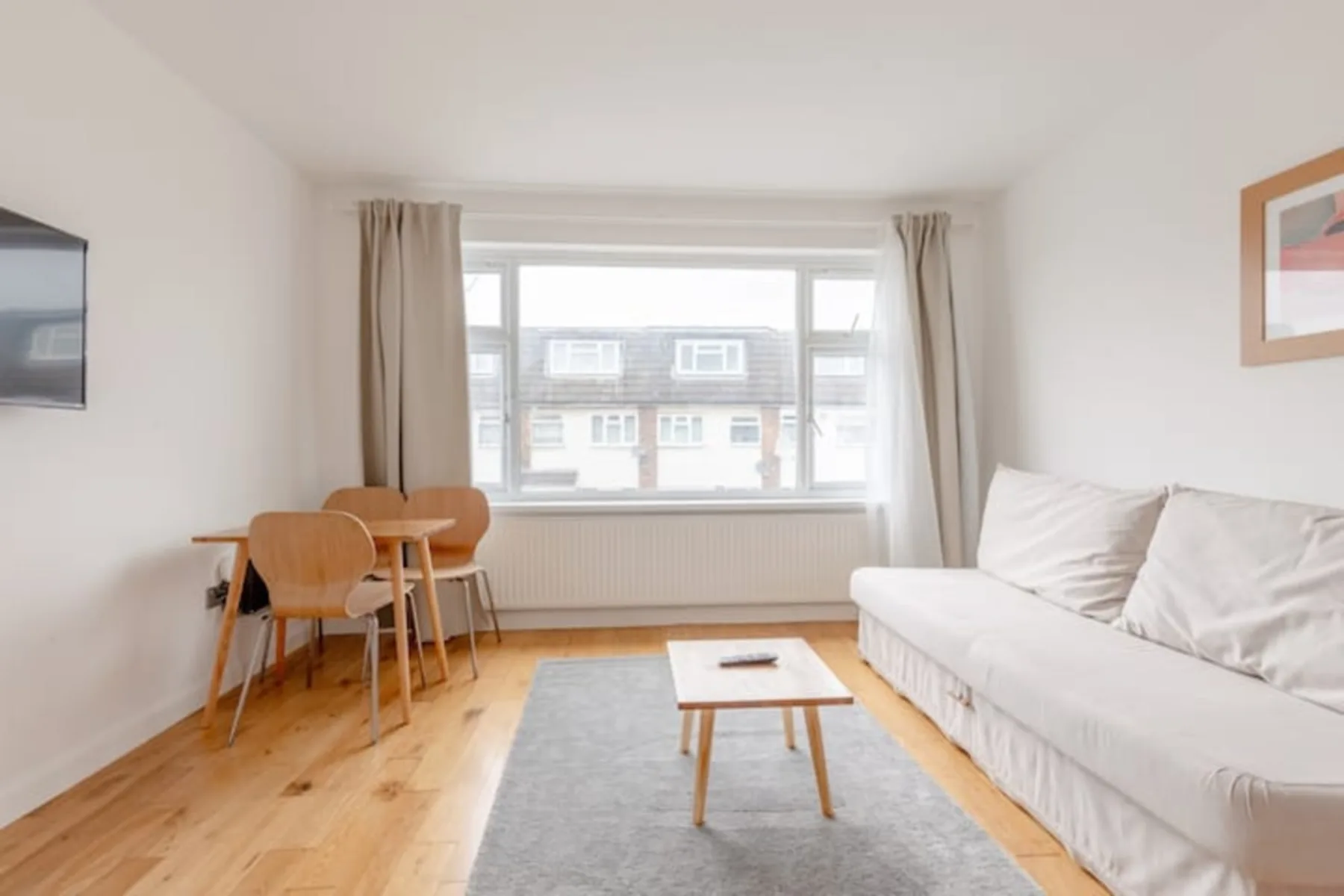 Una sala luminosa con asientos alrededor de una mesa pequeña y una ventana amplia.