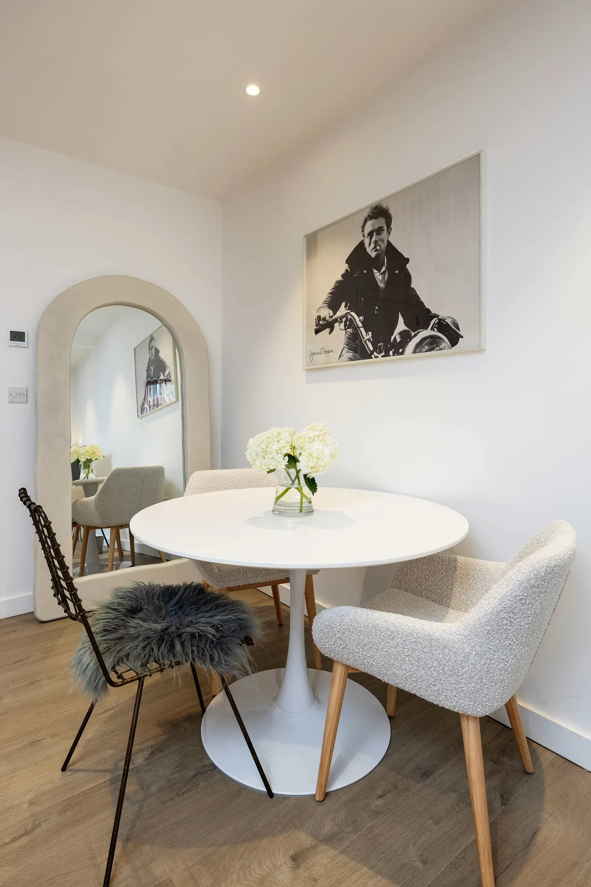 Dining area with a round table and chairs beneath a framed black-and-white photograph.