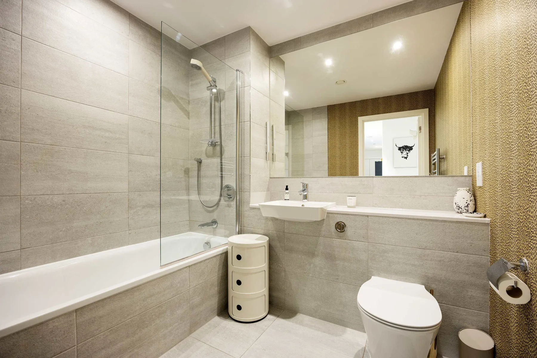A modern bathroom with a bathtub, shower, sink, and toilet.