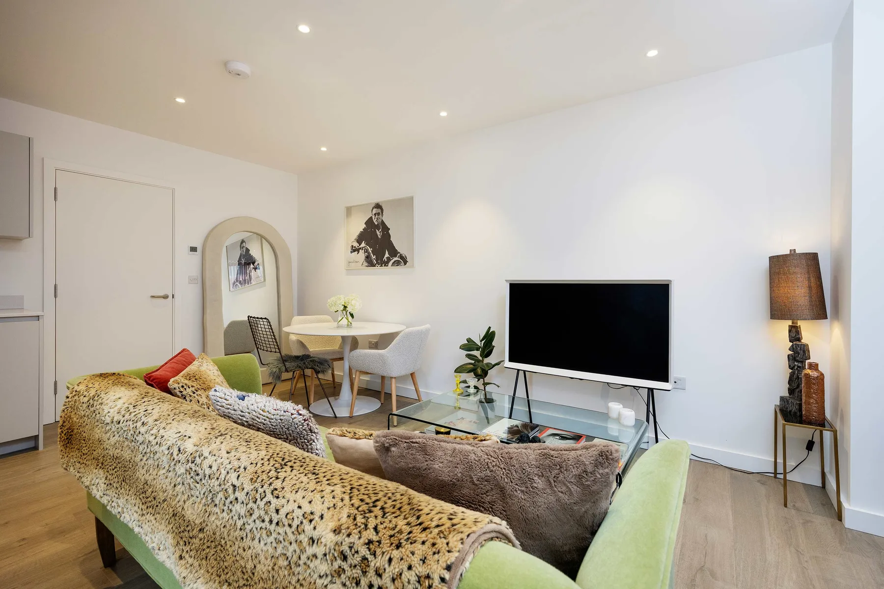 A bright living room with seating, a television, and a small dining area.
