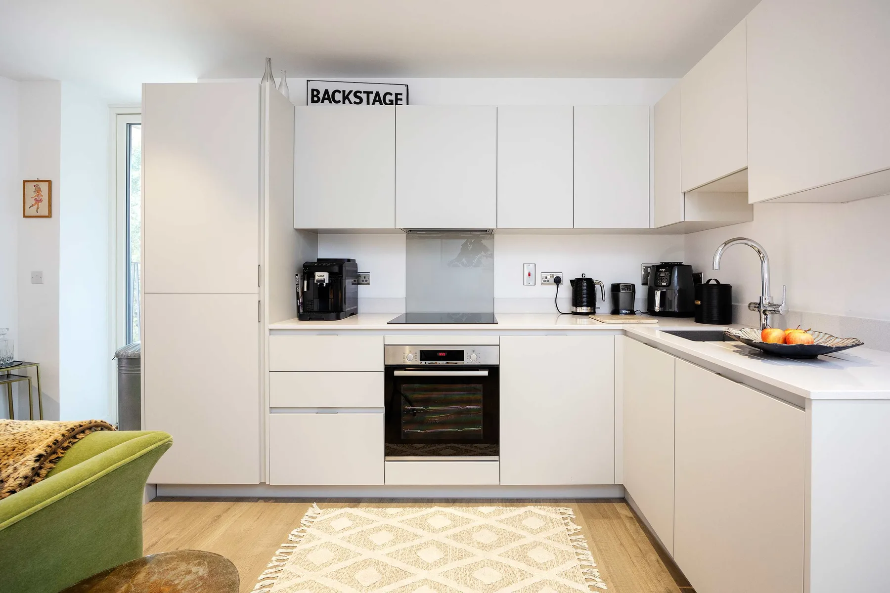 A bright kitchen with white cabinets, a built-in oven, and a countertop.