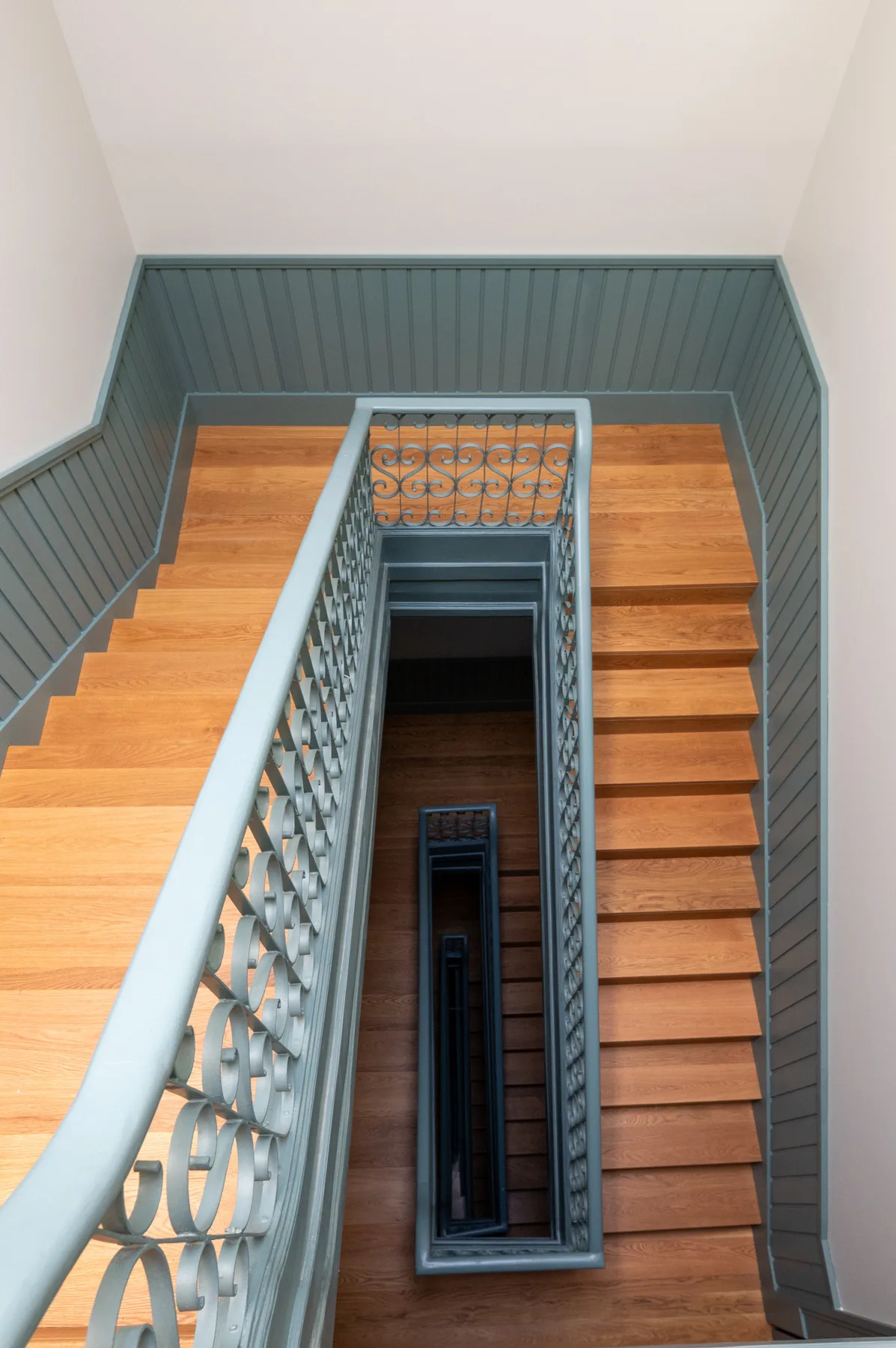 A wooden staircase with decorative metal railings descends through the interior.