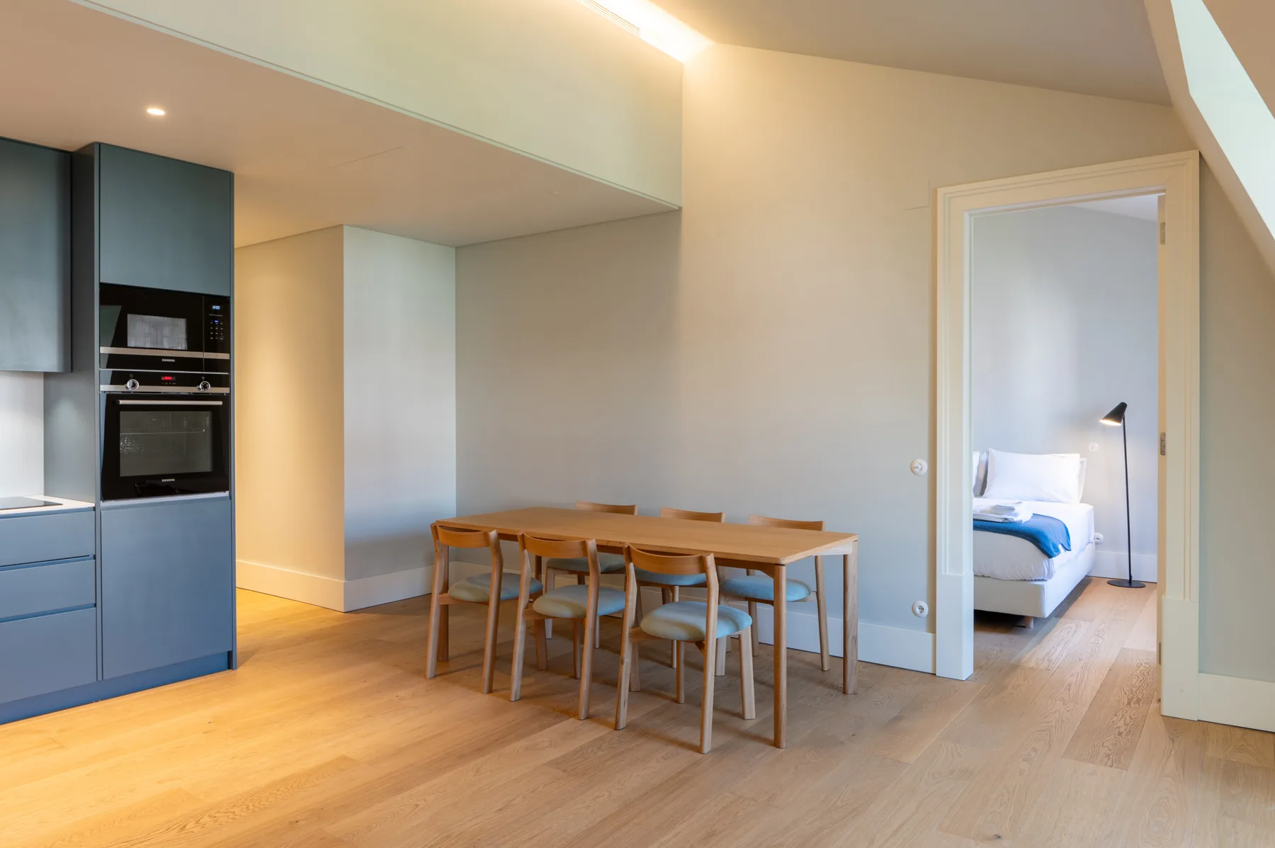 An open-plan kitchen and dining area with a wooden table and chairs.