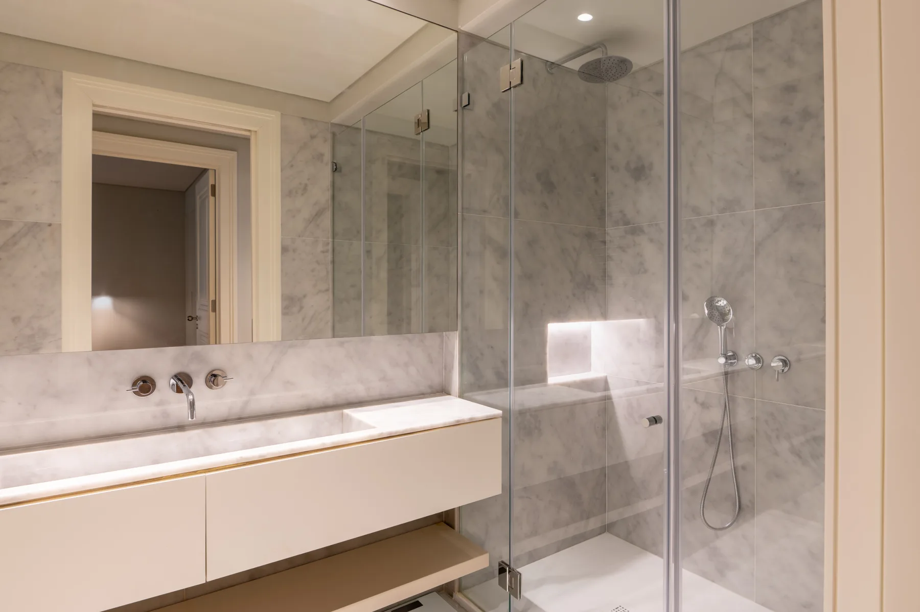 Un baño luminoso con un lavabo largo y una ducha con mampara de vidrio.